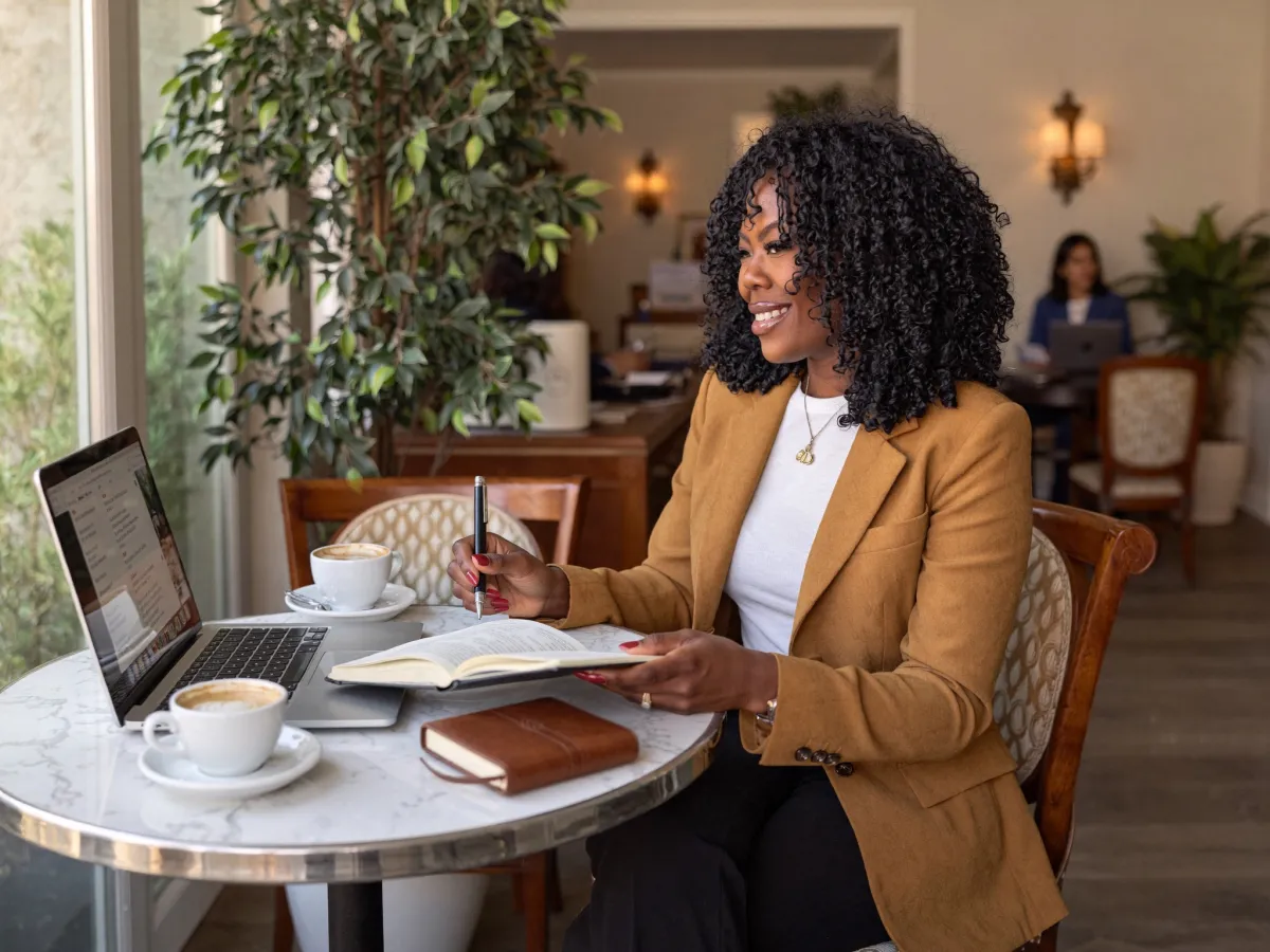 Zuleema Isaac working on a laptop and taking notes at a coffee shop table